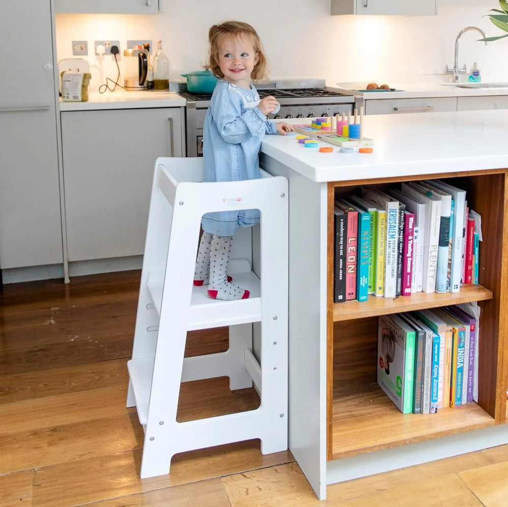 image showing a child in white toddler tower playing with wooden toy